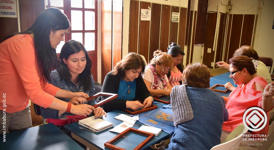 Personas en situación de movilidad humana trabajando en el taller de tejido con mullos.